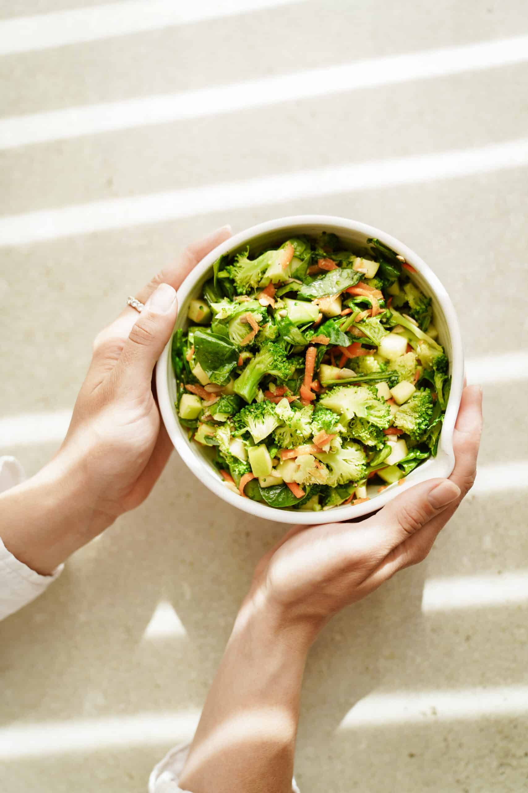 Hands holding a broccoli salad