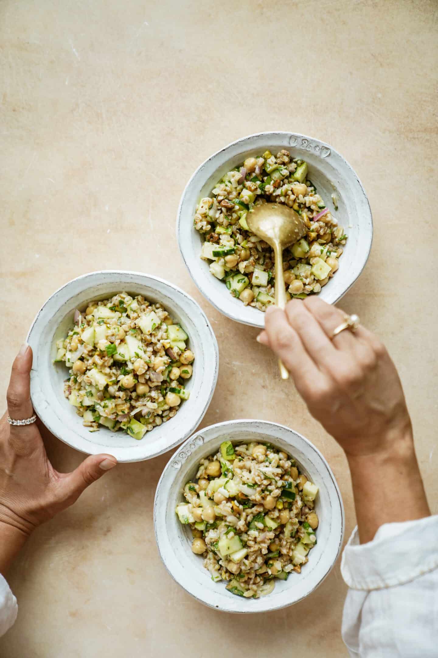 Hand scooping farro salad out of bowl