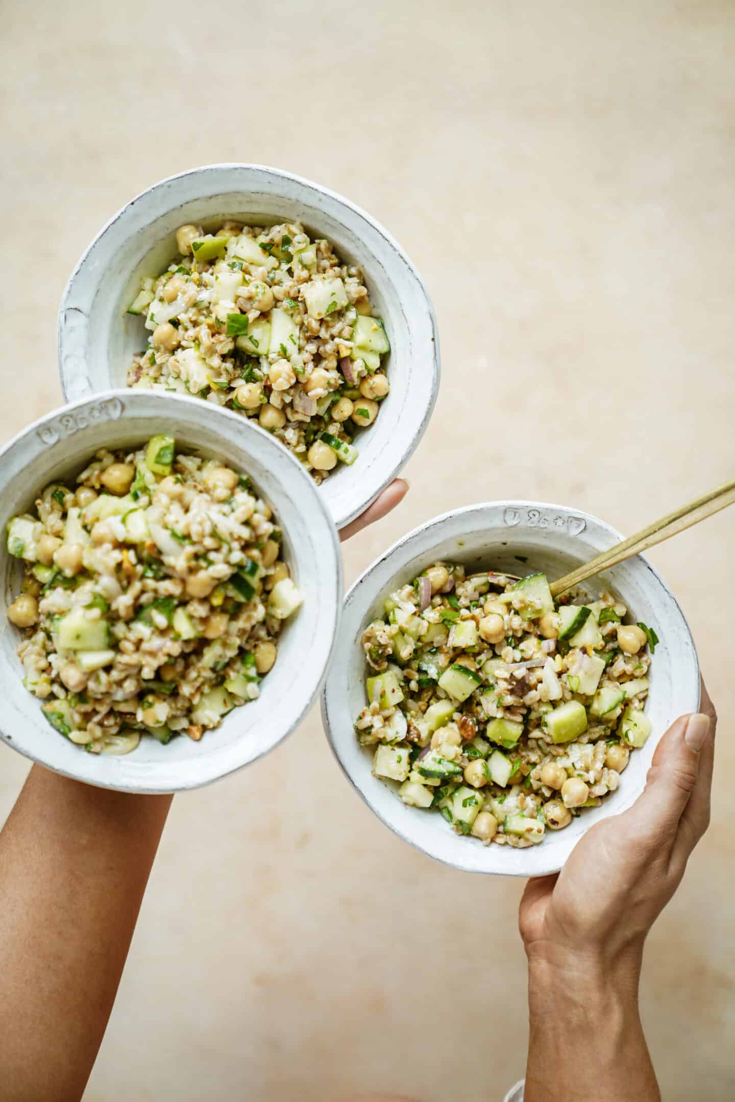 Hand juggling multiple bowls of farro salad