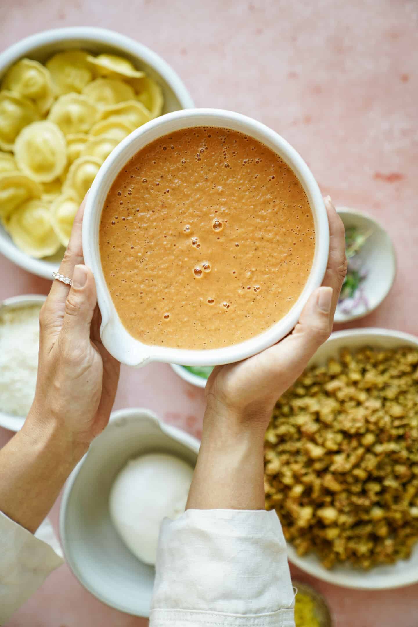 Hands holding marinara sauce in a bowl