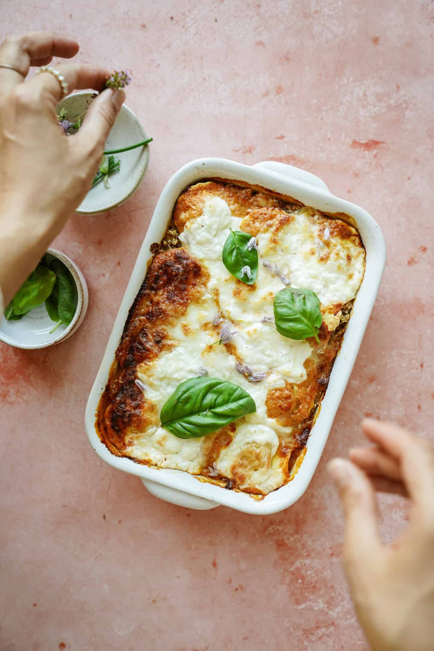 Hands assembling ravioli casserole