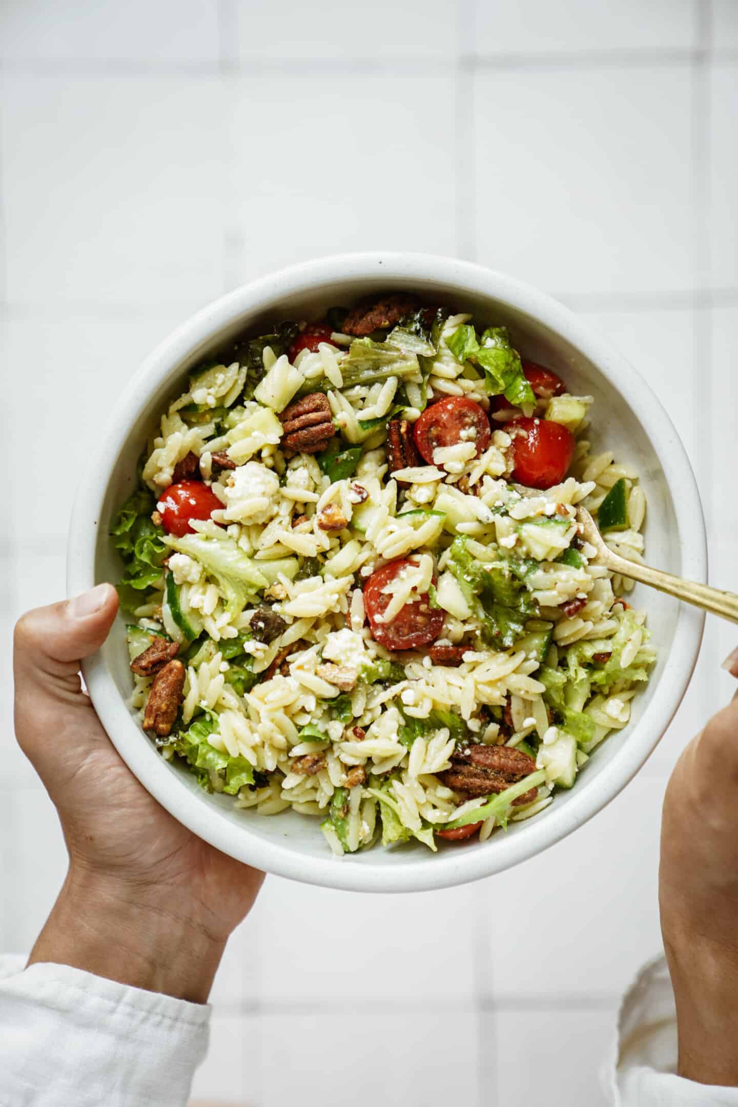 Hand holding a summer salad with a spoon