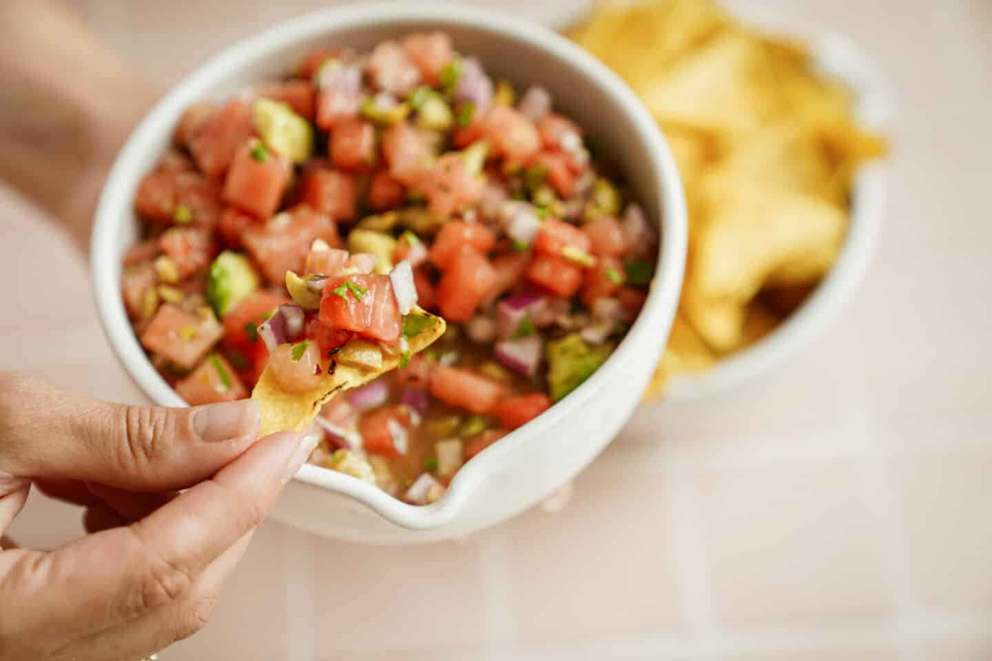 Close up of hand dipping chip into vegan ceviche