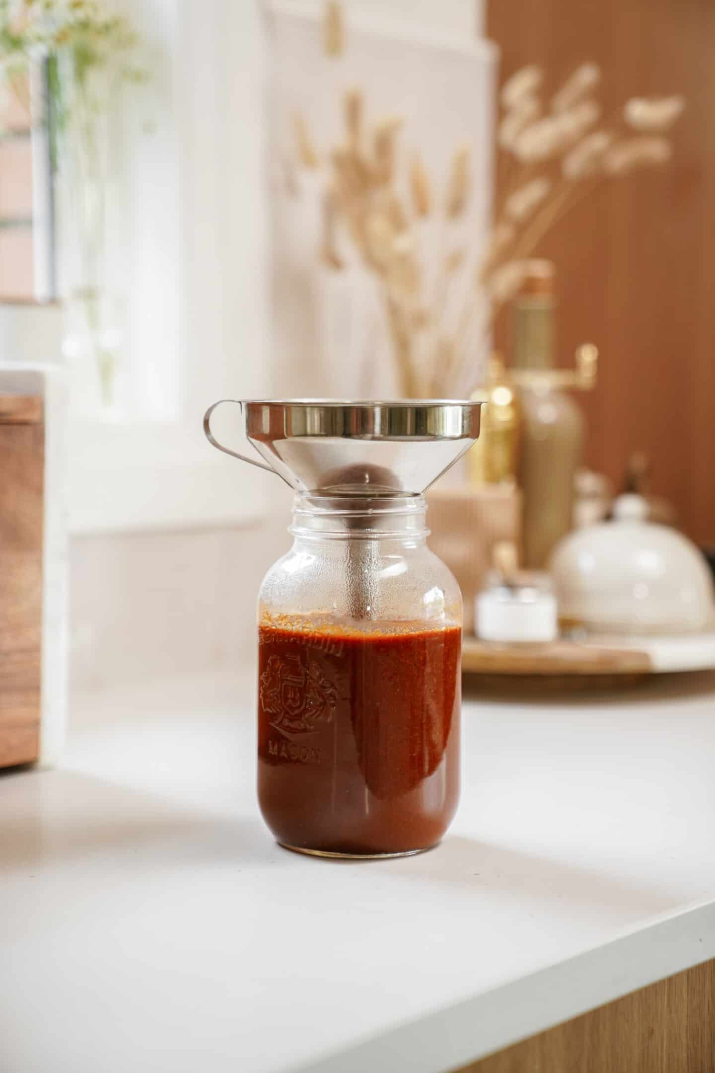 Homemade BBQ sauce being poured into a jar