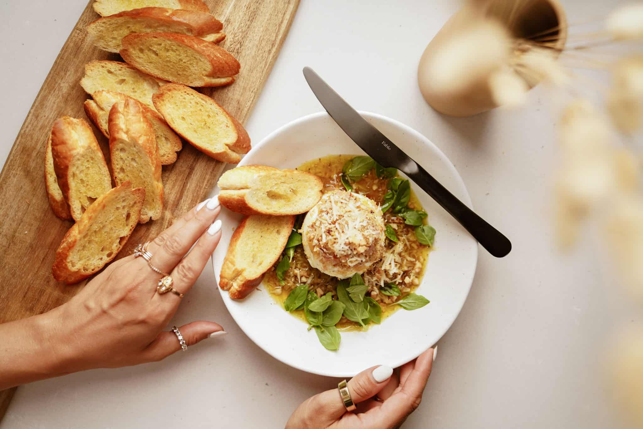 Burrata cheese on a dish next to a cutting board with bread