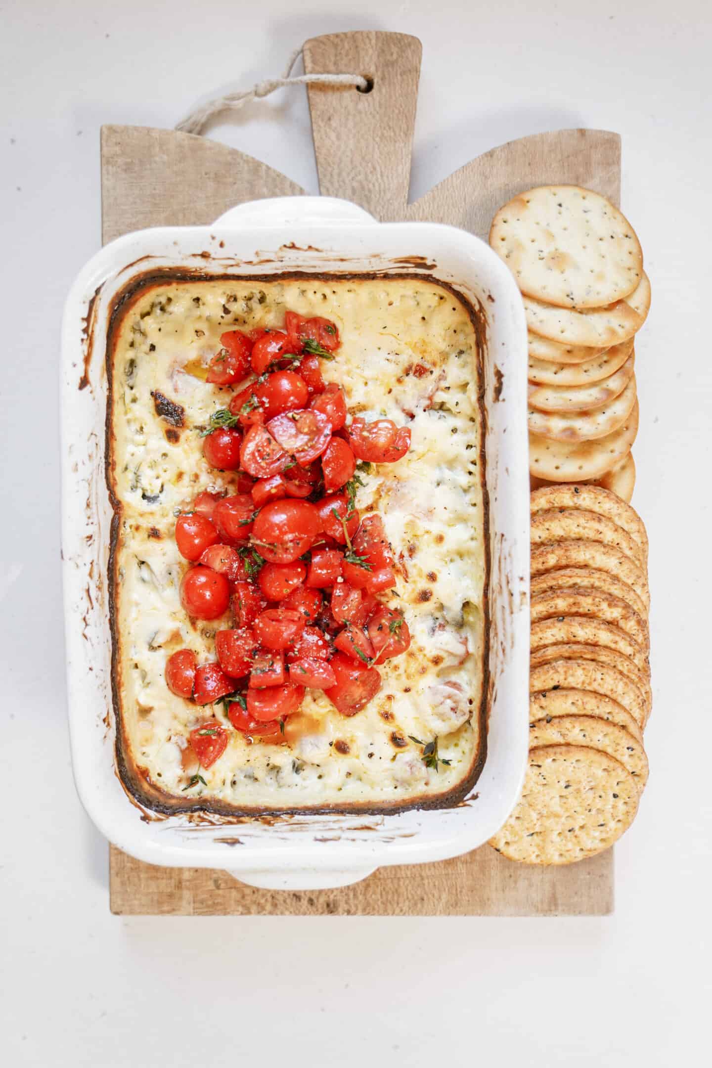 Baked feta dip on a cutting board with crackers