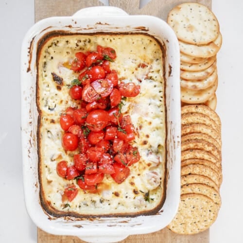 Baked feta dip on a cutting board with crackers