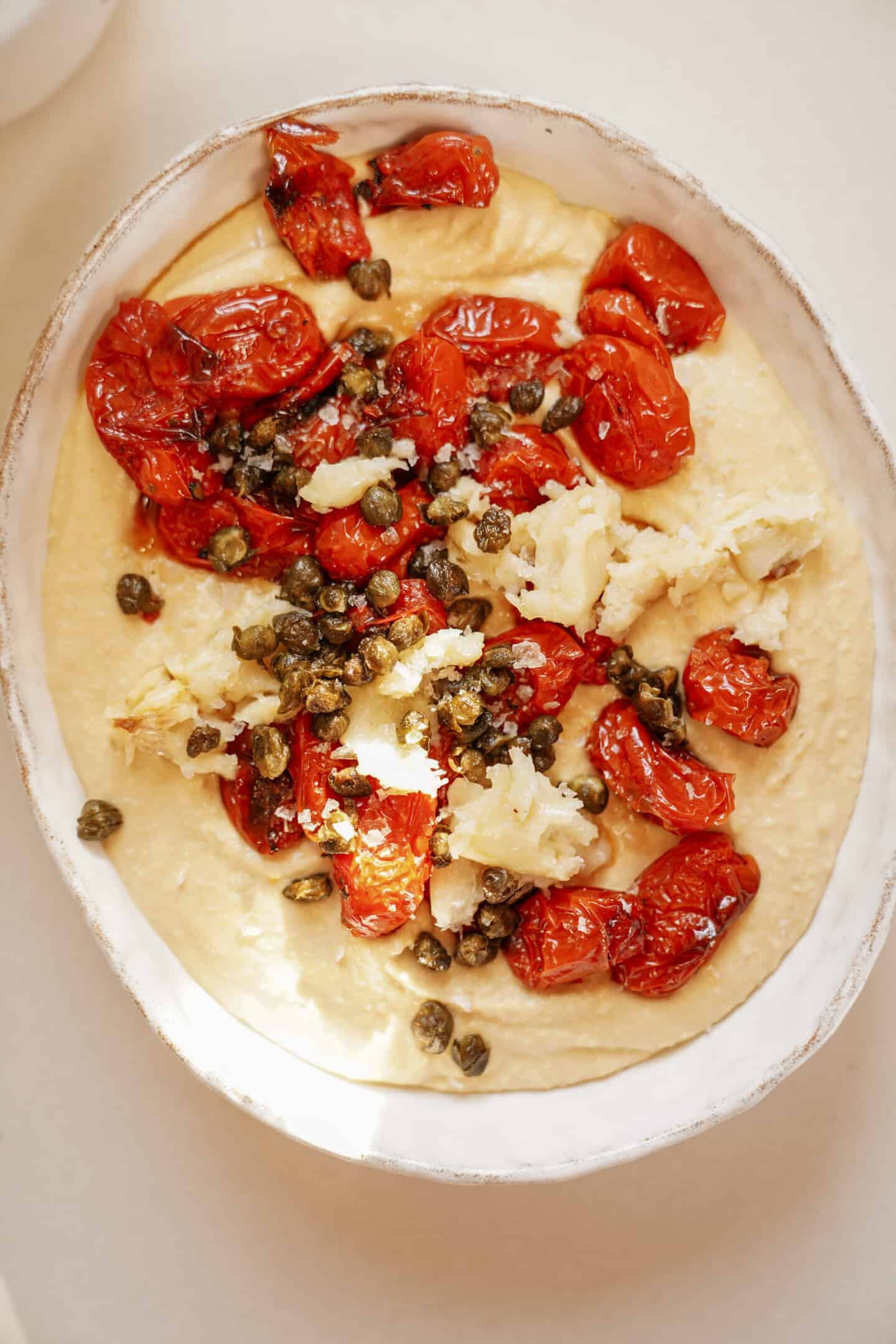 Easy hummus recipe with tomatoes and garlic on top