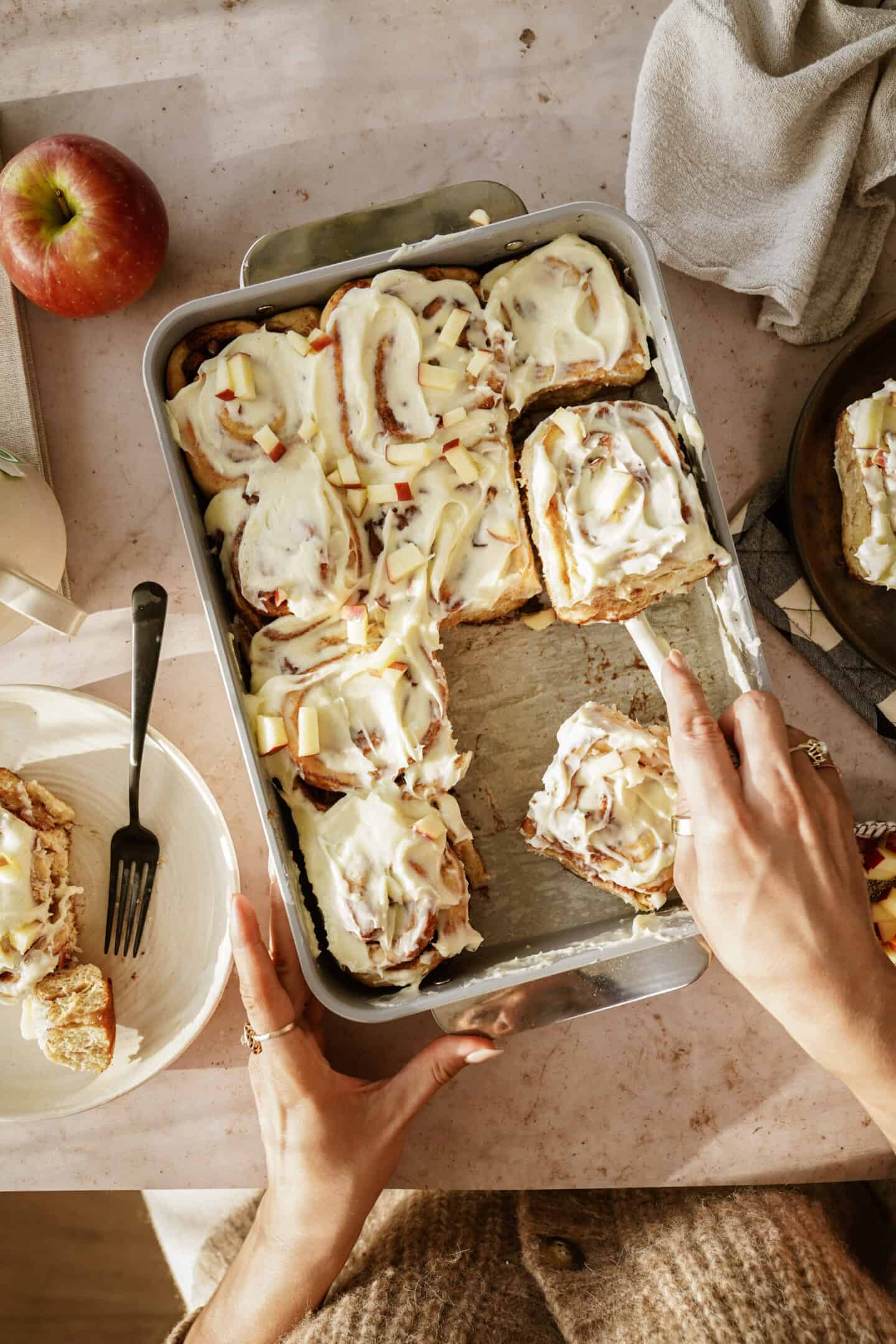 Cinnamon roll recipe in a serving dish with a hand serving