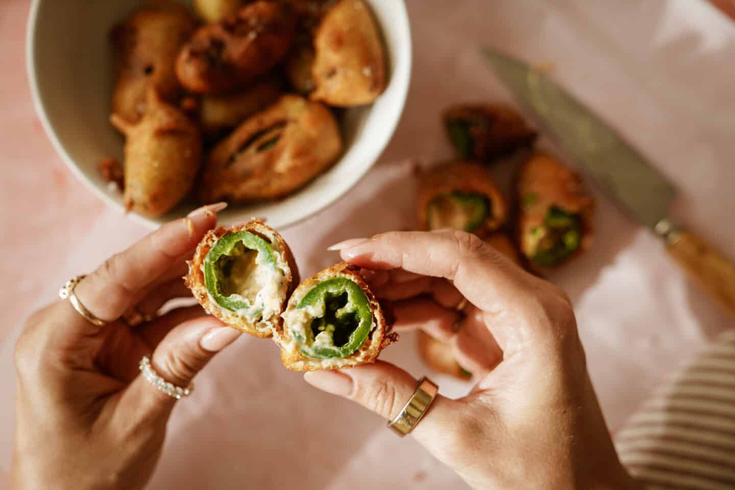 Hands holding a cracked opened stuffed jalapeno popper