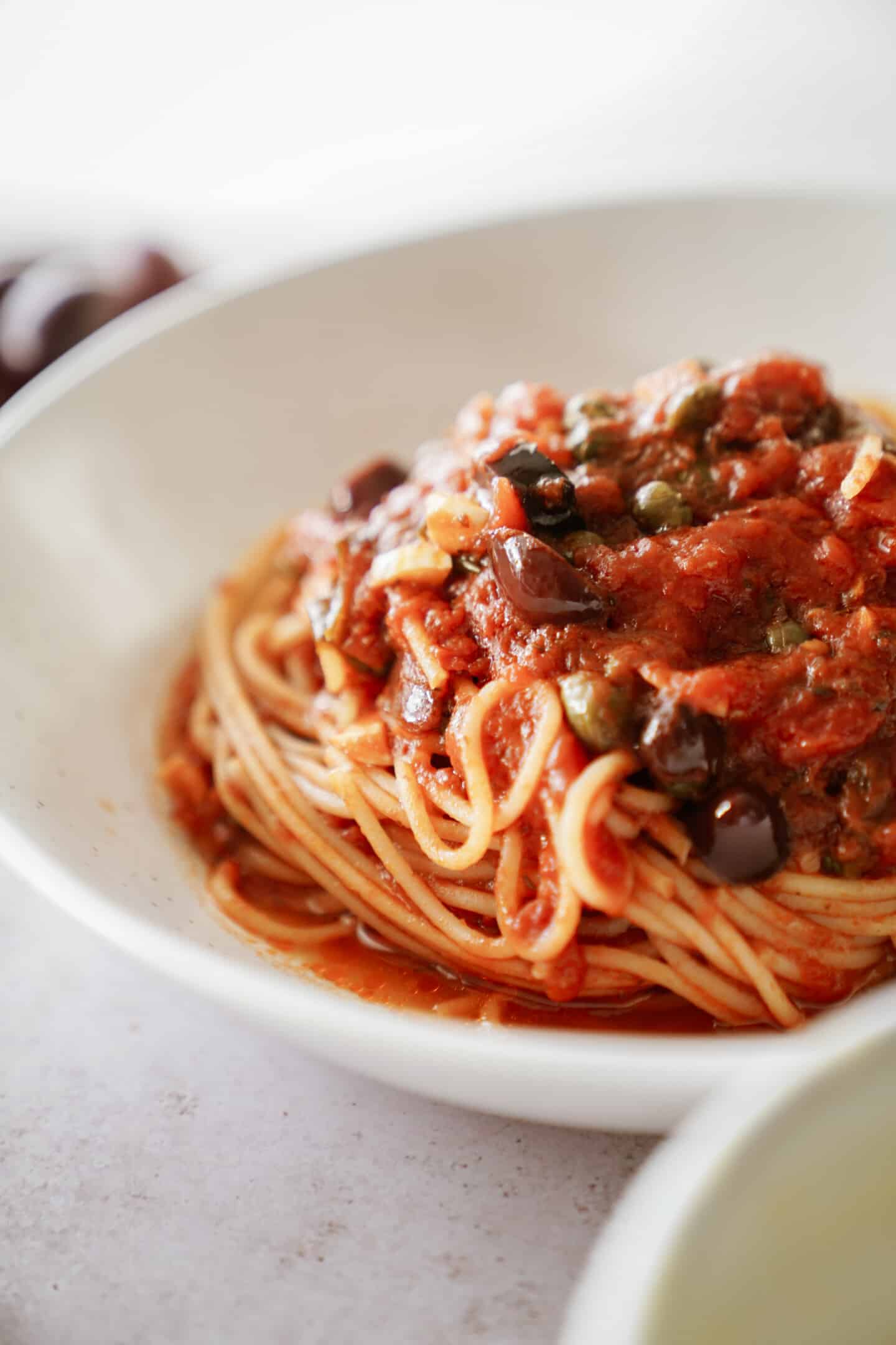 Puttanesca pasta in a white bowl