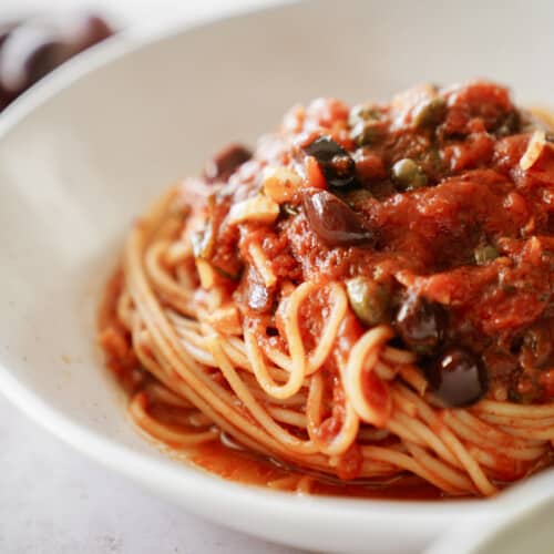 Puttanesca pasta in a white bowl