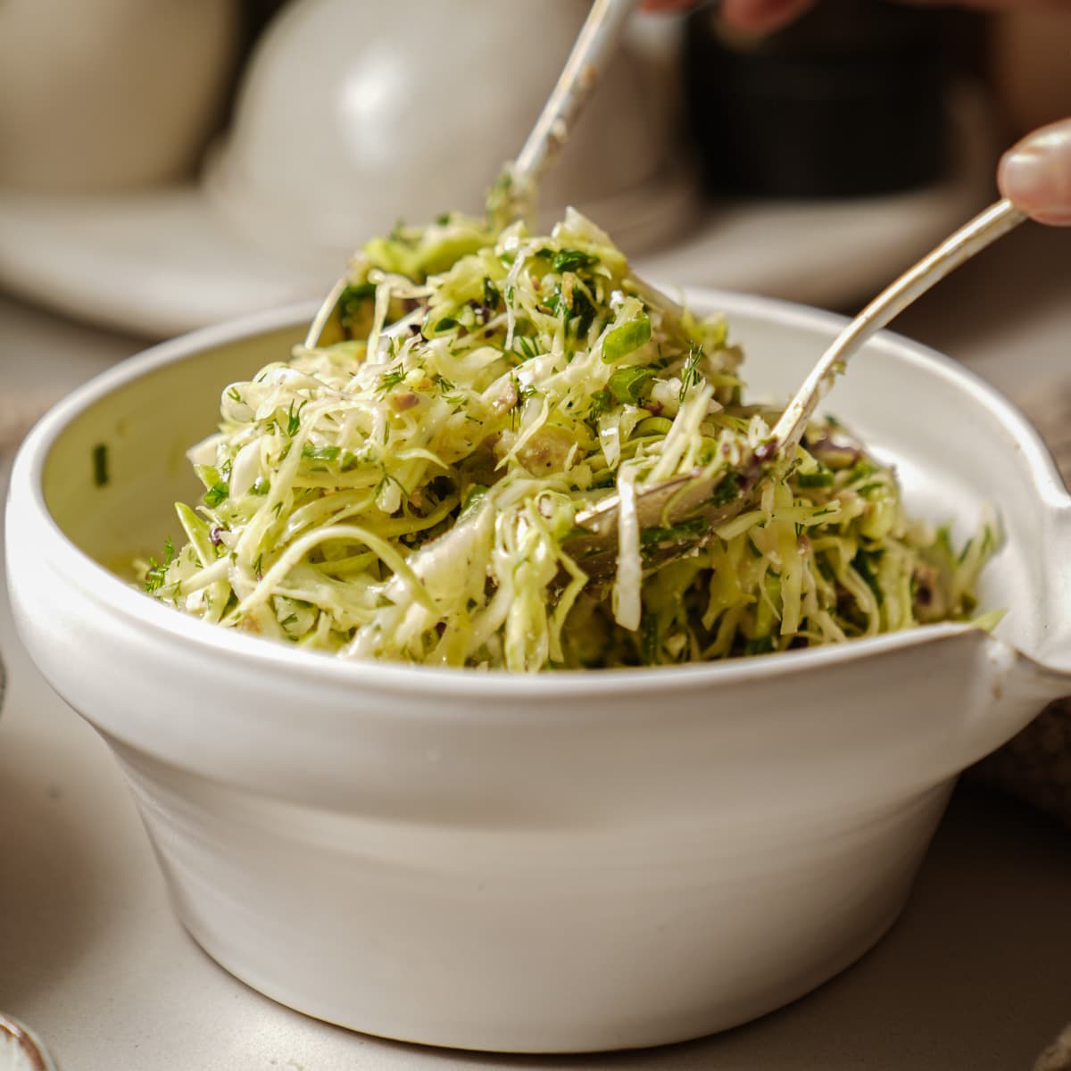 Bowl of Greek cabbage salad with serving spoons in it