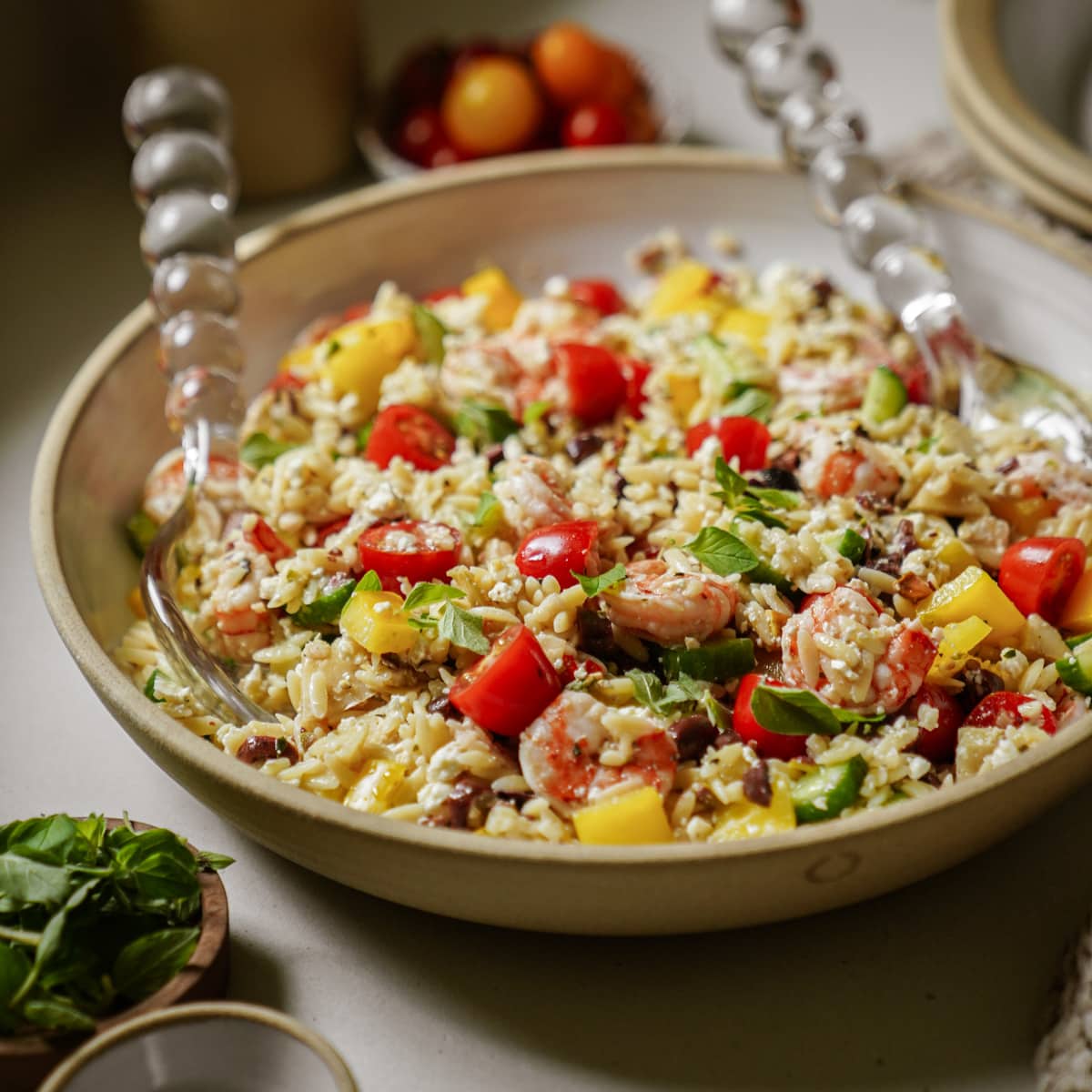 Serving bowl with spoons of orzo pasta salad