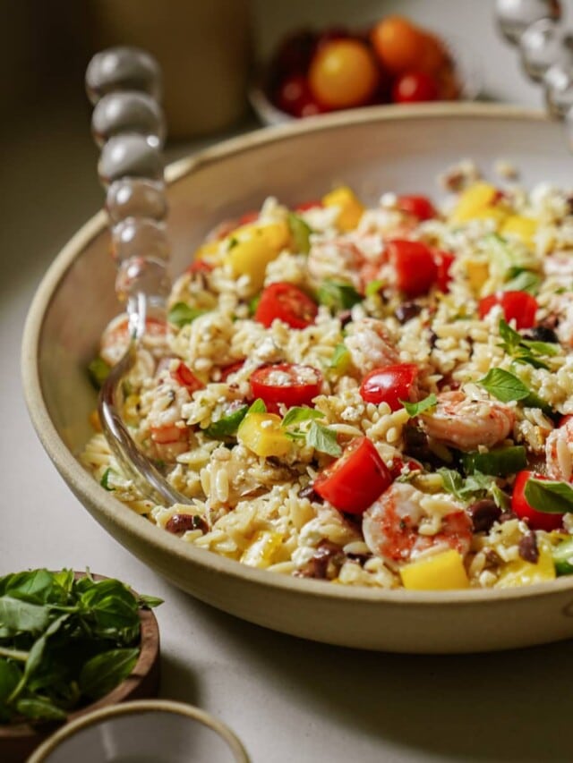 Serving bowl with spoons of orzo pasta salad