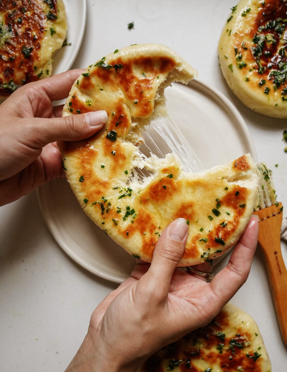 Hands holding a fluffy pita bread