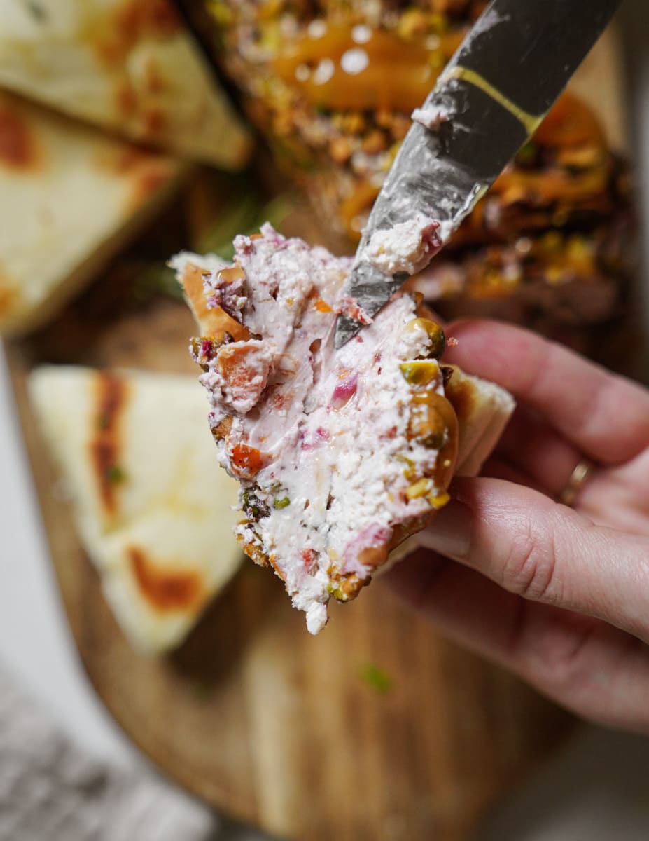 Cheese log being spread on bread