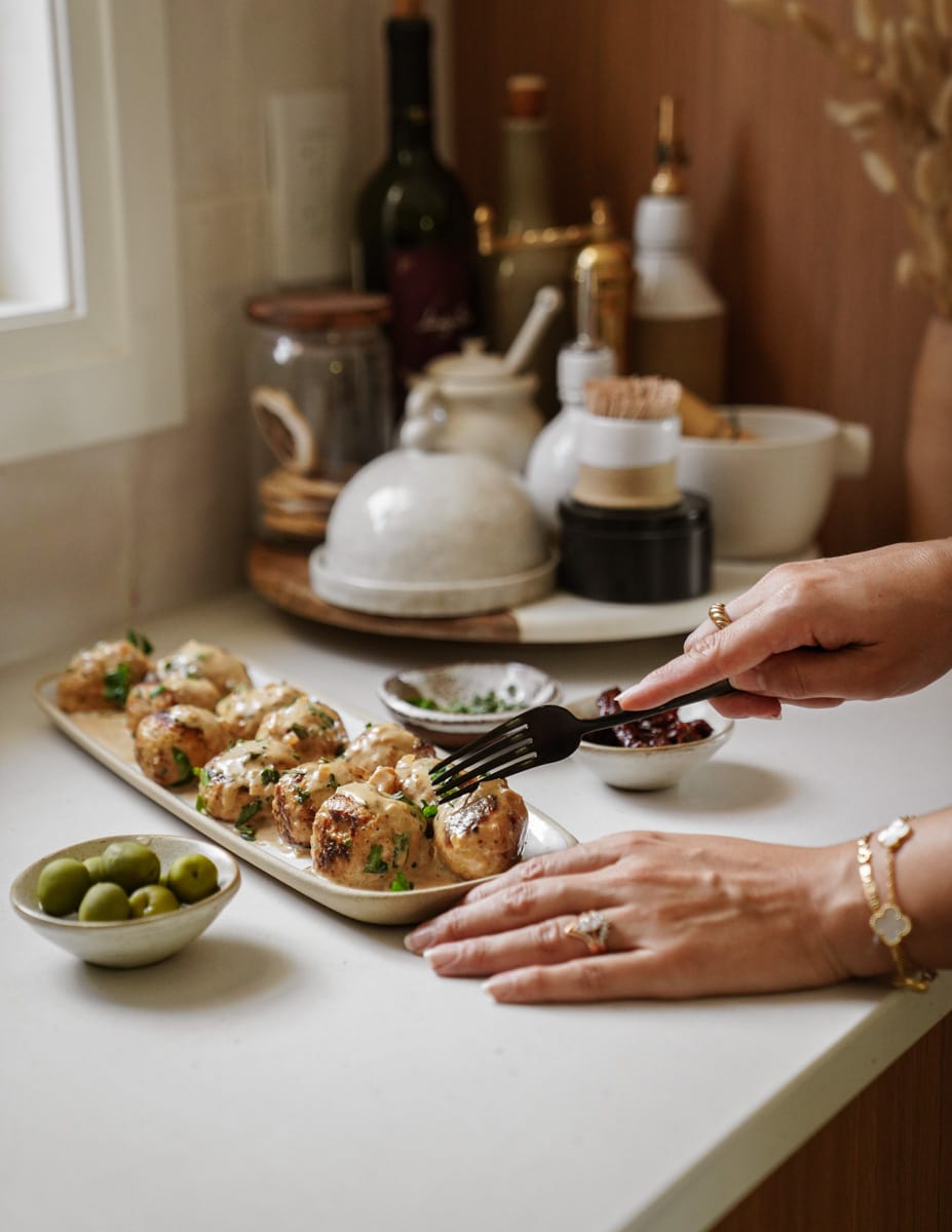 Hand serving chicken meatballs on a platter