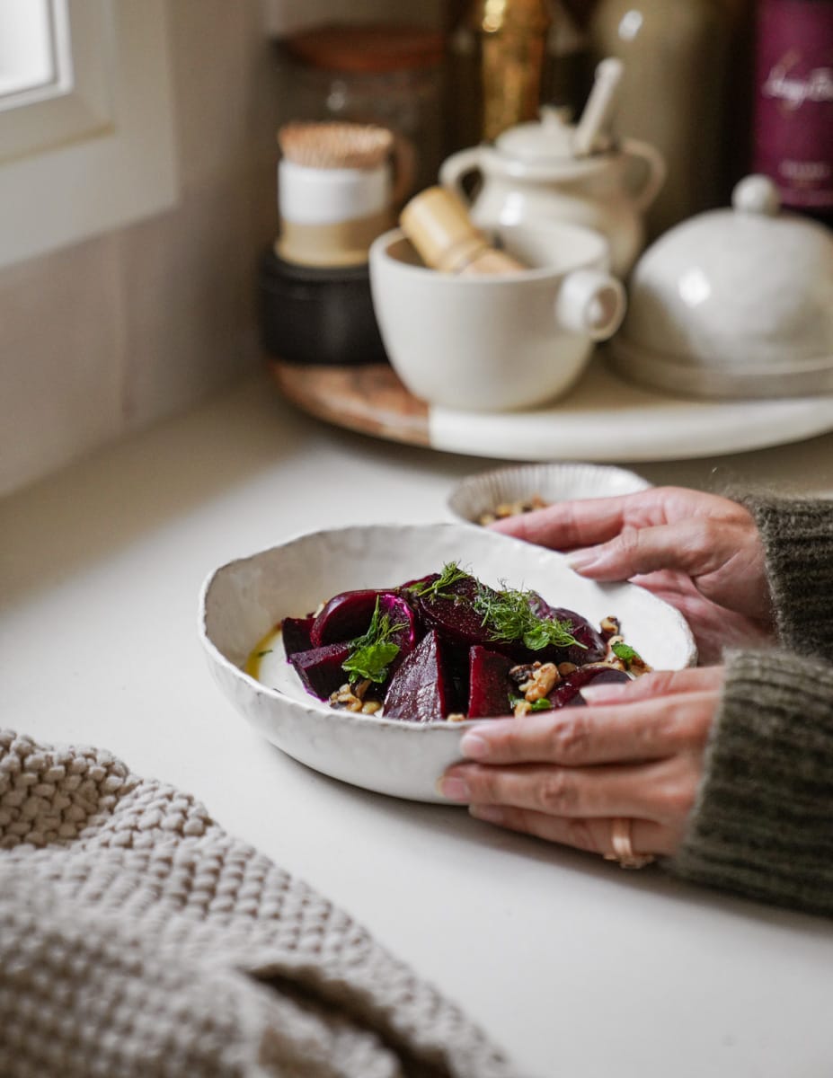 Hands holding a bowl with roasted beet salad in it