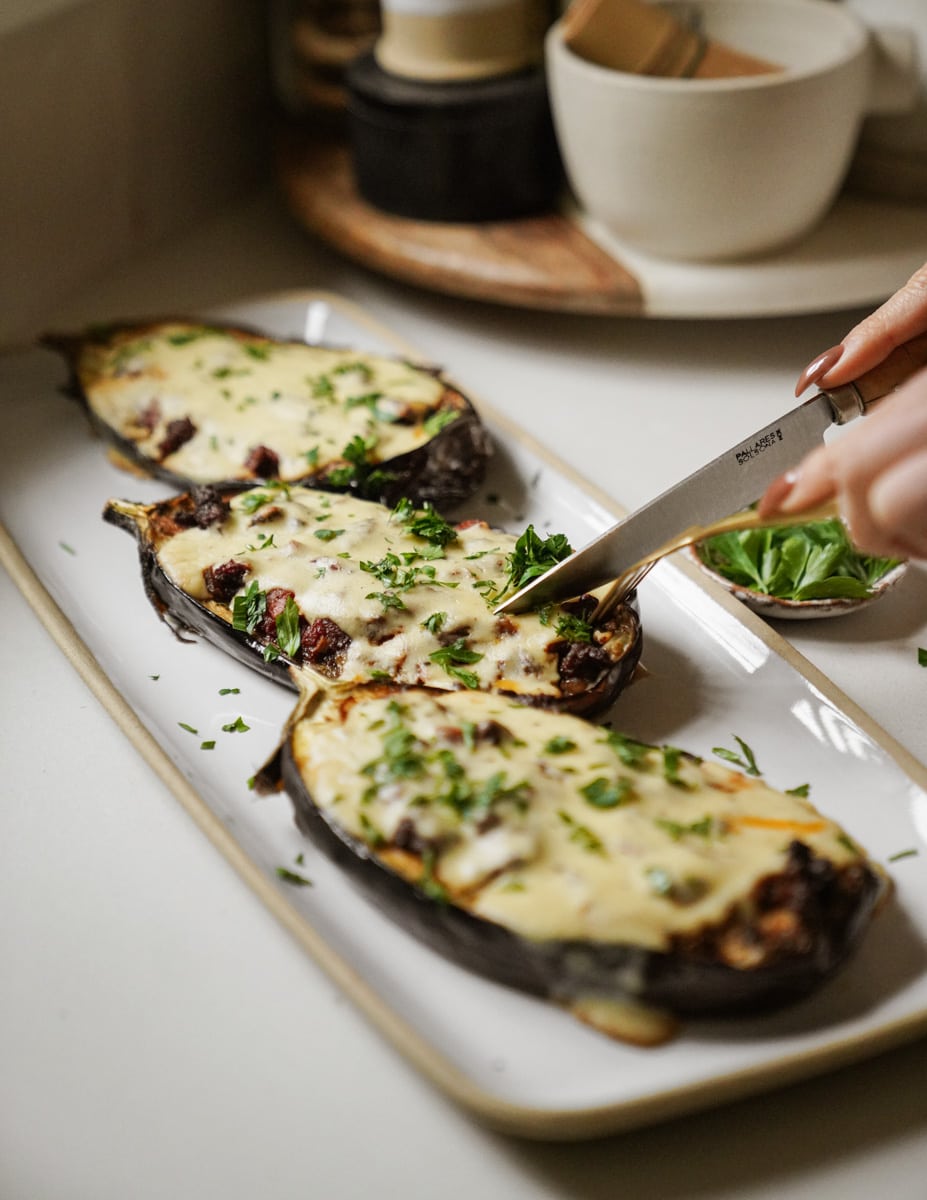 Knife and fork cutting into Greek stuffed eggplant