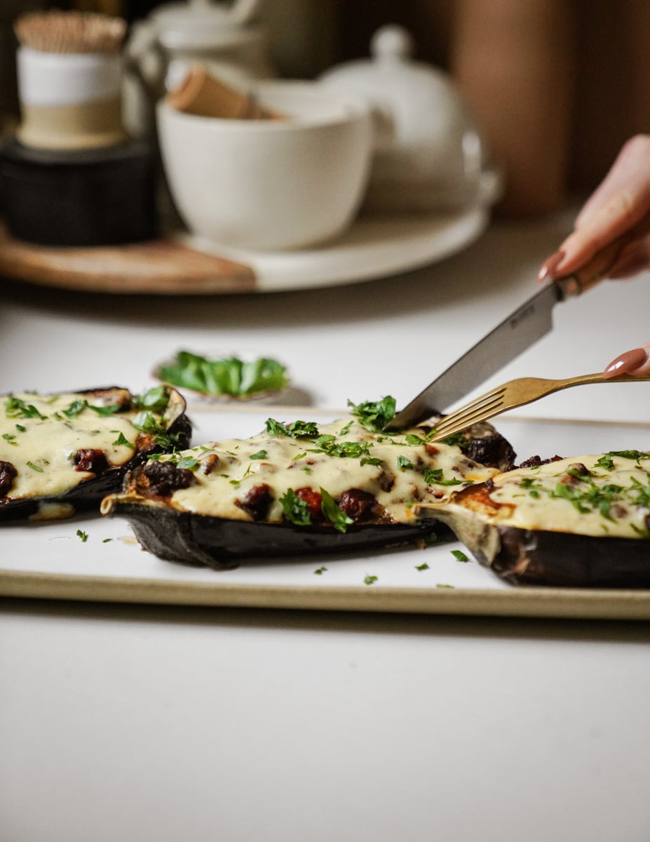 Side view of stuffed eggplant being cut into on a plate