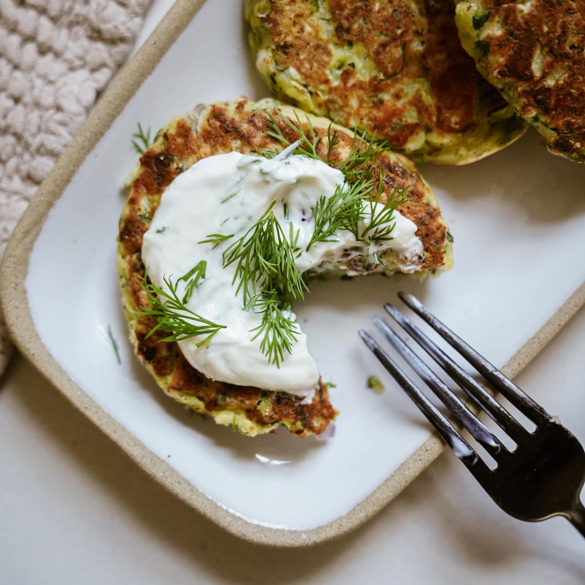 Close up of a zucchini fritter with a piece bit out of it and a fork