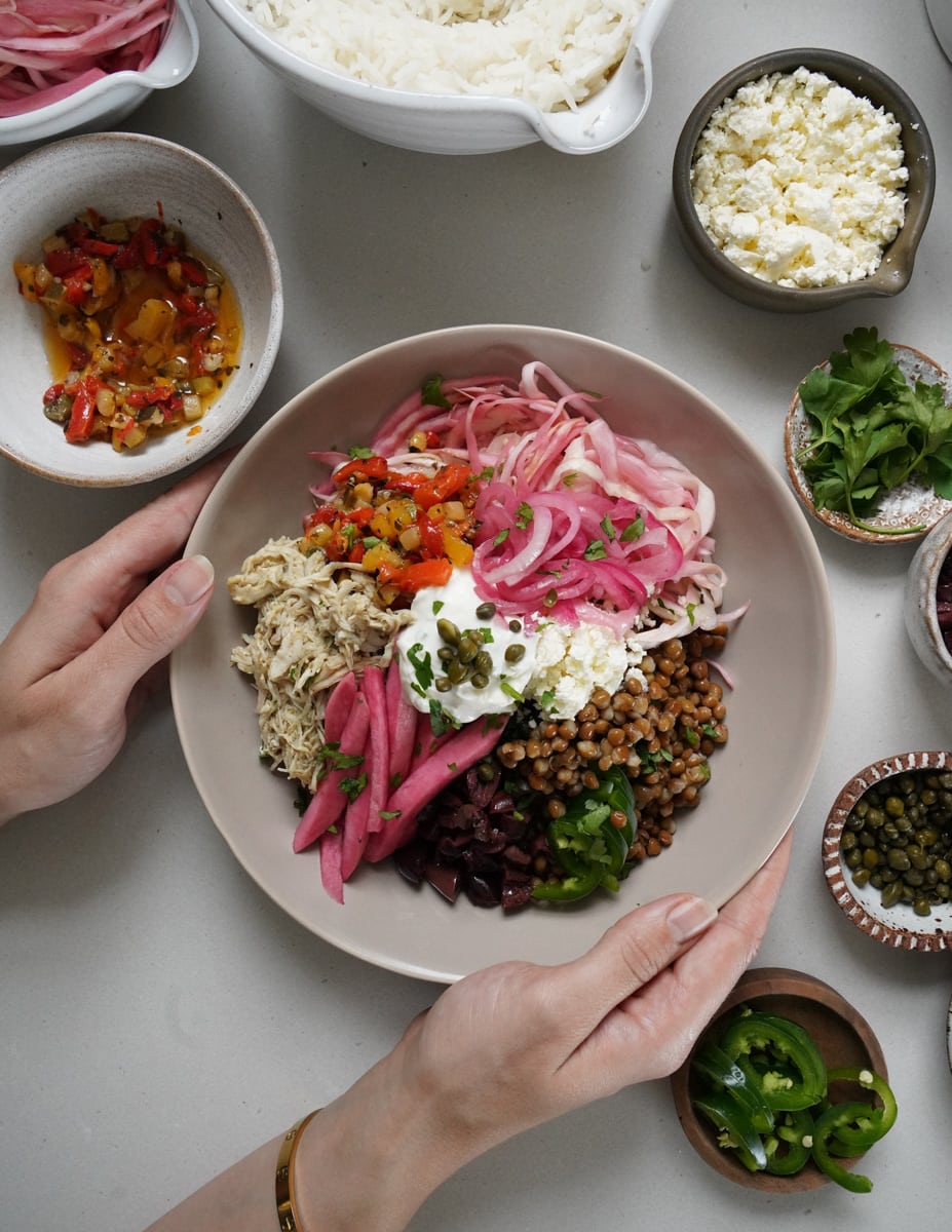 Hands holding a cava bowl with ingredients surrounding it