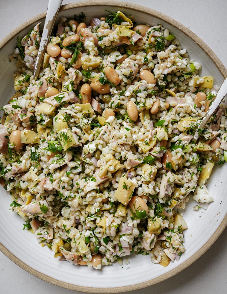 Mixed healthy chicken salad in a bowl with serving spoons