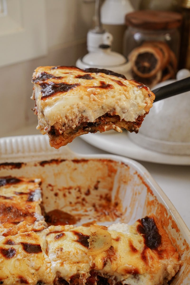 Greek Moussaka being taken out of a baking dish