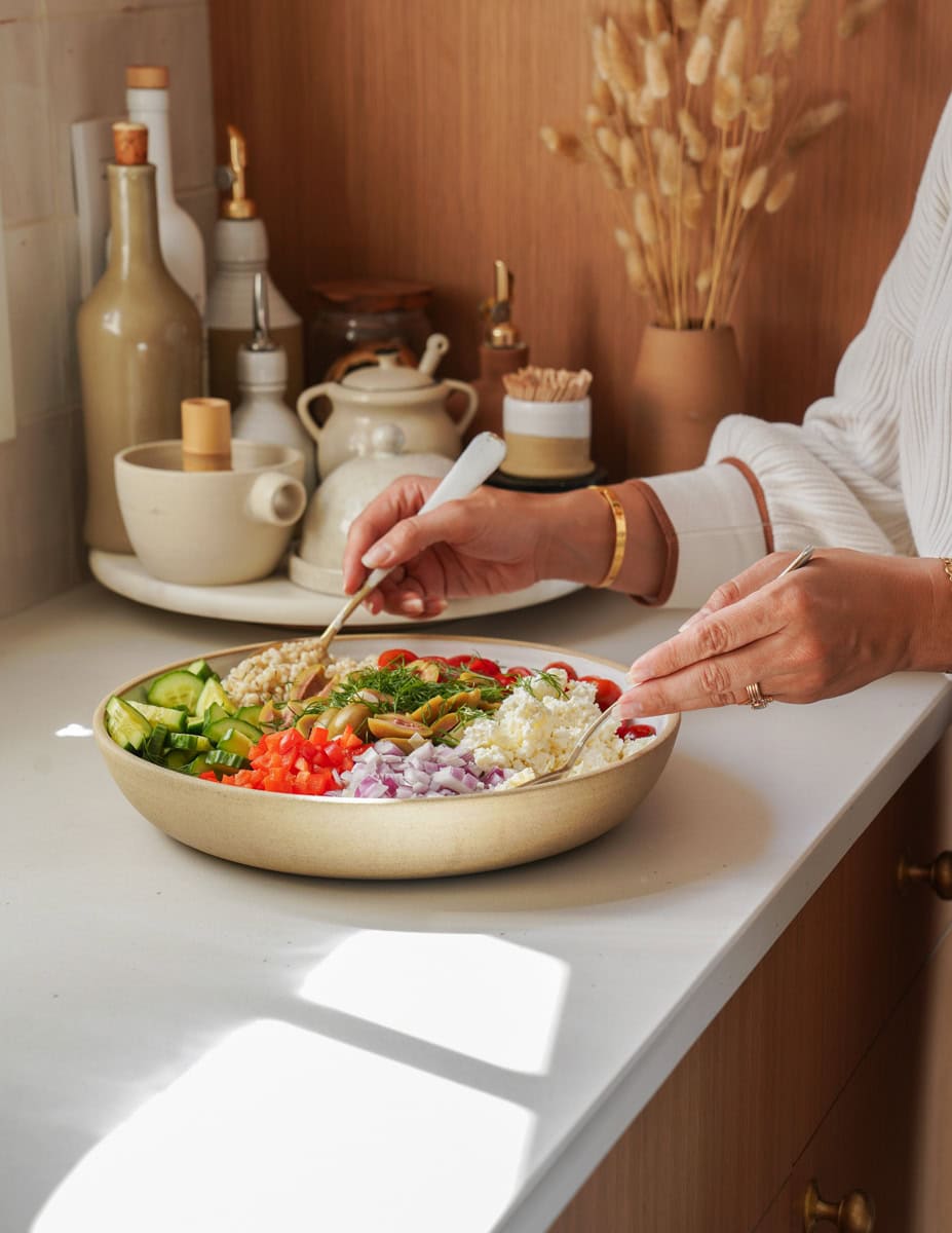 Hands mixing a Barley Salad in a white bowl