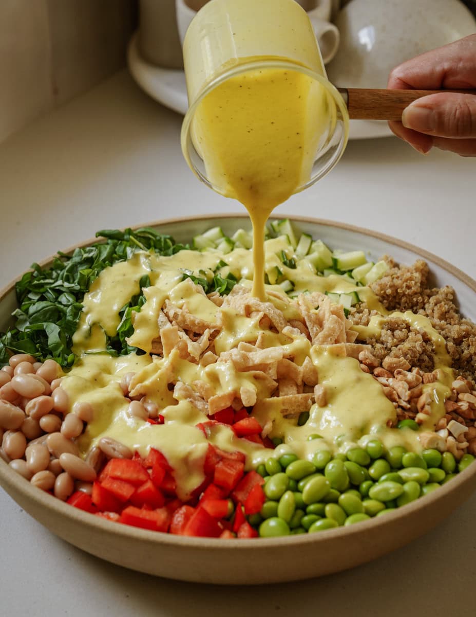 Dressing being poured on edamame salad