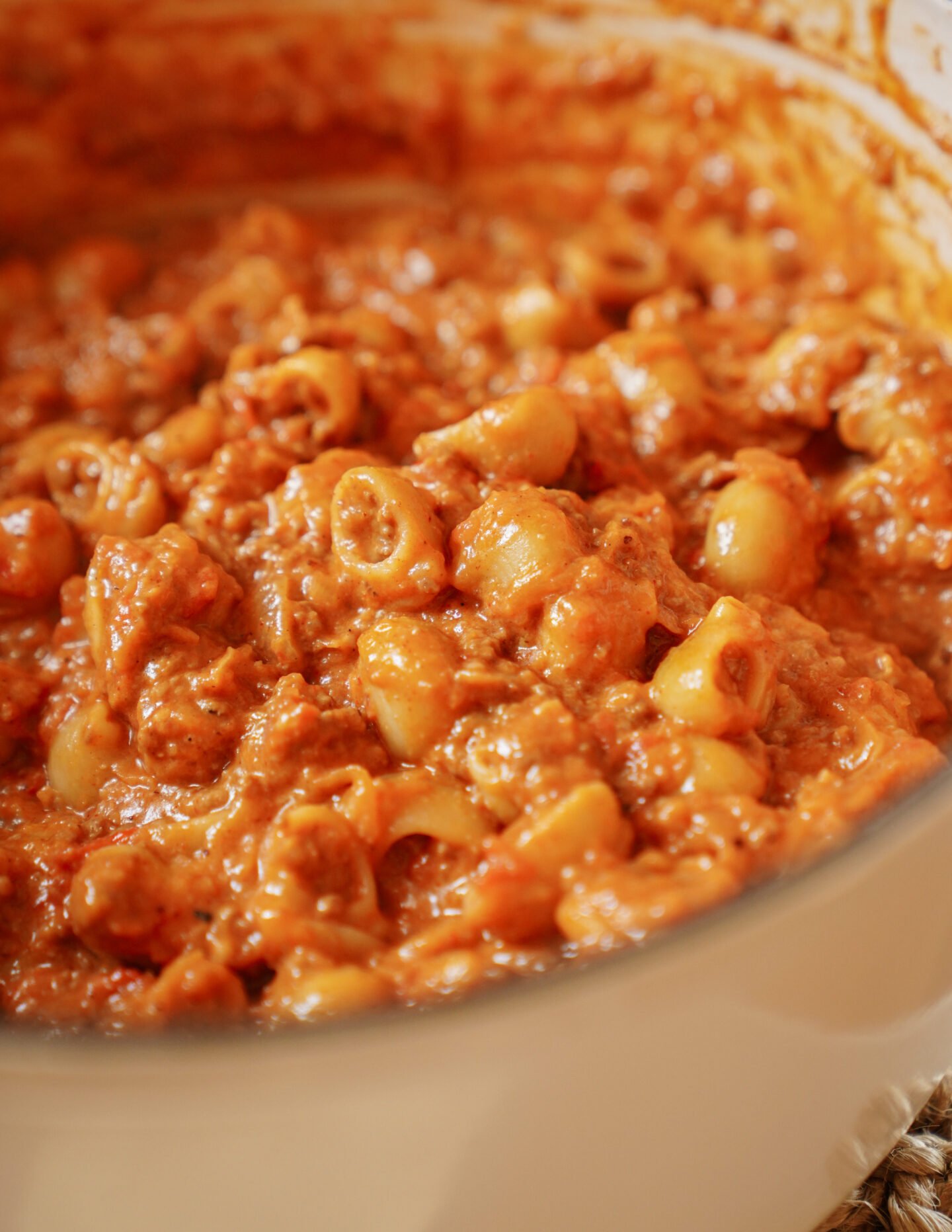 A close-up of creamy pasta with a tomato-based meat sauce, featuring small pasta shapes coated in a rich, orange-red sauce inside a white pot.